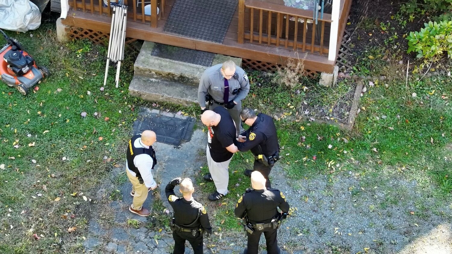 Suspect Joseph Bell, center, is taken into custody outside of his residence without incident.